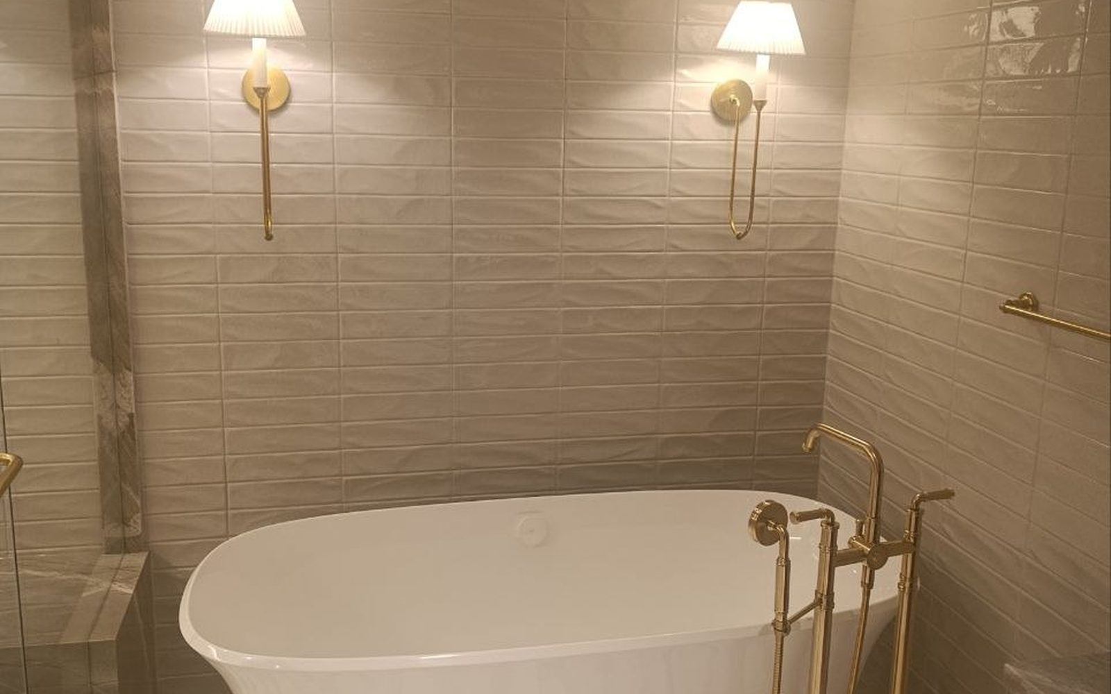 Finished spa ensuite built by Lions Group: freestanding oval tub with a brass floor filler, warm wall sconces and a patterned stone floor